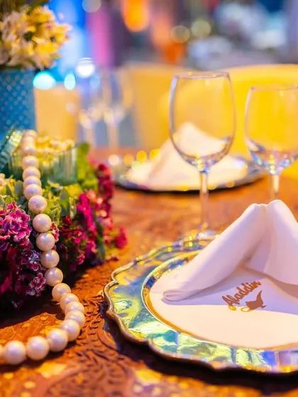 A close-up of the table setting from the Aladdin party. The details include iridescent charger plates and custom napkins, showing how the theme is carried through to the smallest elements.