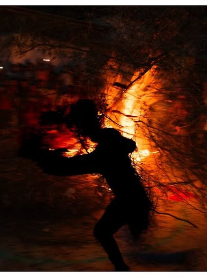 A motion-blurred shot of a person running with a flaming torch during Holika Dahan celebrations in Jodhpur. The image captures the chaotic energy and ancient symbolism of the Holi festival.