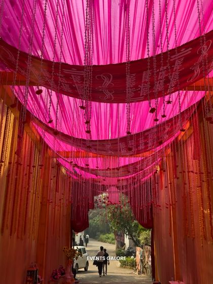 The entrance to the Vidhi Mandap was a tunnel of vibrant pink and orange drapes with hanging floral strings, creating a warm and festive welcome for the guests.