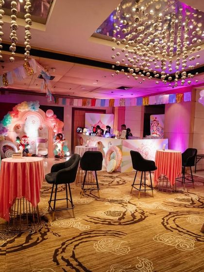 A wide view of the party space, showing the themed bar, high top tables, and main stage area.