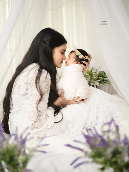 A mother and her newborn share a sweet nose-to-nose moment. This intimate shot, framed by soft white curtains, is the definition of pure love.