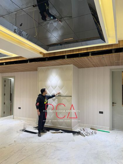 A work-in-progress shot from the Outram Lines residence, showing a team member inspecting a newly installed, intricately carved wall panel.