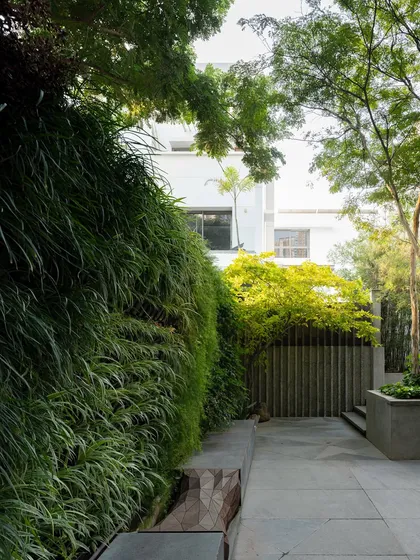 A lush vertical garden wall serves as a living backdrop for a custom-designed bench with sculptural elements. The design integrates art directly into the planting, creating a multi-layered and textured composition.