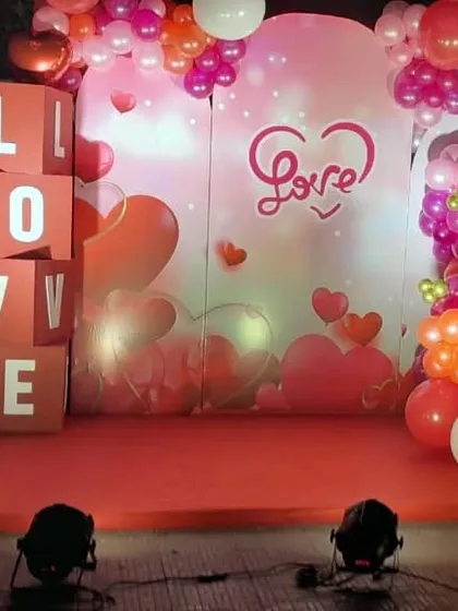 A romantic photo stage with a "Love" theme, perfect for anniversaries or Valentine's events. The setup includes a themed backdrop, "LOVE" letter blocks, and a colorful balloon arrangement.