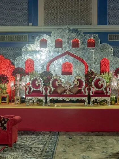 The main stage for a red-themed wedding, featuring a silver-leafed backdrop in the shape of a palace facade, flanked by walls of red roses.