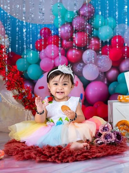 Welcome to cookie land! This wide shot shows the full, vibrant setup with balloons, donuts, and a happy toddler.