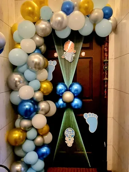 An elegant door decoration to welcome a baby boy, using a blue and silver balloon garland and sheer fabric.