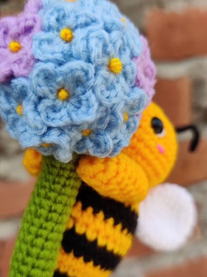 A custom-made keychain featuring a happy little bee holding a handmade hydrangea flower. The level of detail in the tiny petals was a fun challenge.