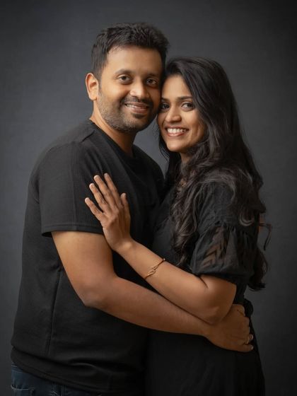 A warm and intimate couple's portrait. The simple dark background keeps the focus entirely on their connection and happy smiles.