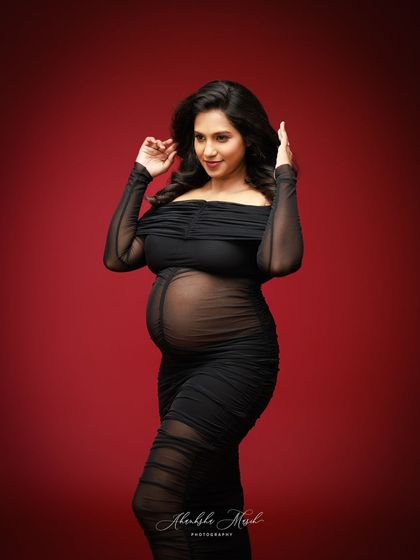 A joyful and confident pose in a sheer black ruched gown, celebrating the beauty and strength of the expectant mother.
