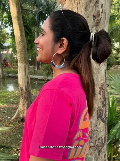 A customer styling the denim blue 'Naazakat' hoops with a bright pink tee. This shows how versatile they are for color-blocking and creating a fun, casual look.