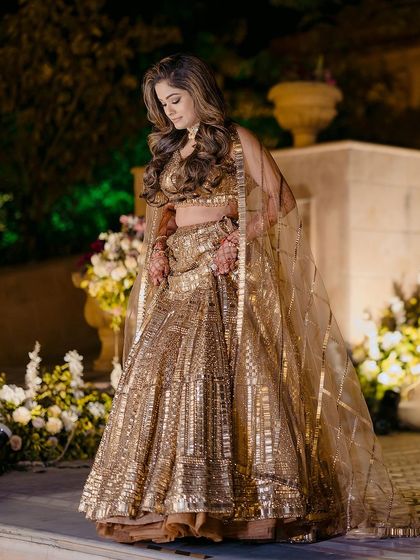 A stunning solo portrait of the bride-to-be in her shimmering golden lehenga, looking every bit the star of the evening.