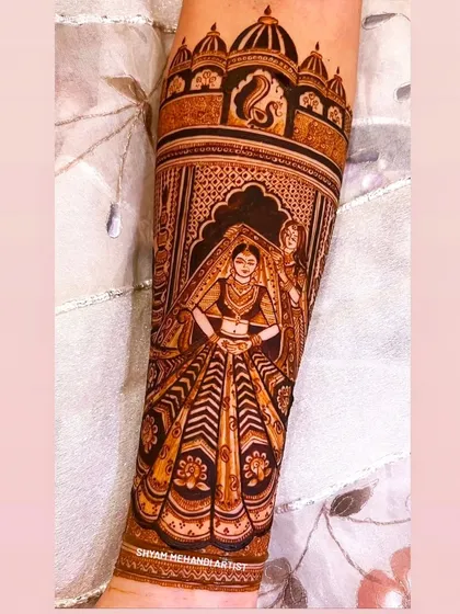 A full-figure portrait of a bride in her stunning lehenga, meticulously detailed on the forearm.