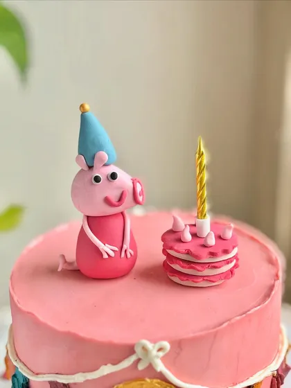 A close-up of the fondant Peppa Pig and her tiny birthday cake, showing the handcrafted details that bring the character to life.