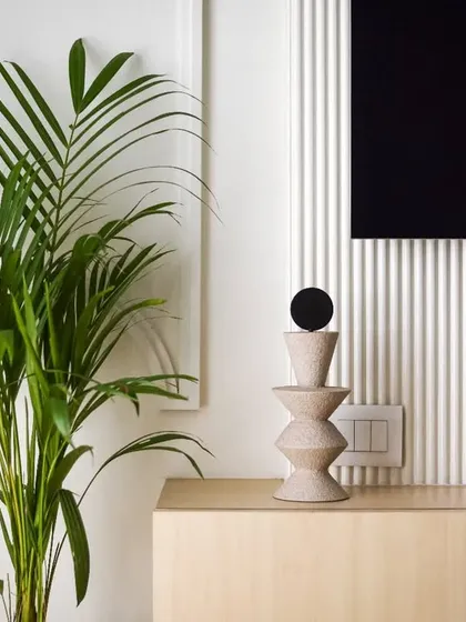 A detail shot of the TV console, with a simple, sculptural decor piece and a large plant adding a touch of nature.
