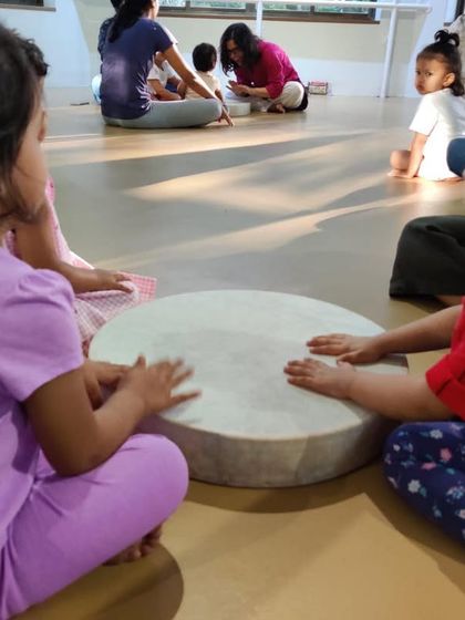 "Listen to me play the drum." This is a moment of pride and accomplishment. Playing an instrument, no matter how simple, builds a child's self esteem and encourages them to share their creations with the group.