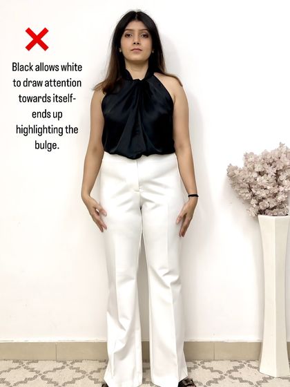 A demonstration of what not to do. Pairing white trousers with a contrasting black top draws attention directly to the midsection, highlighting the tummy bulge.