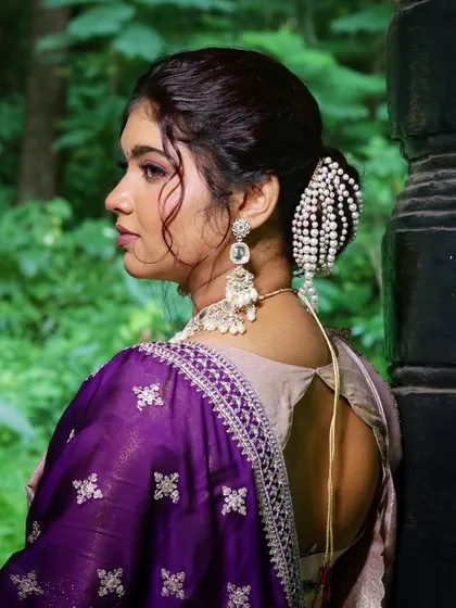 A side profile showcasing an elegant bridal updo with a stunning pearl hair accessory. This hairstyle is both modern and timeless.