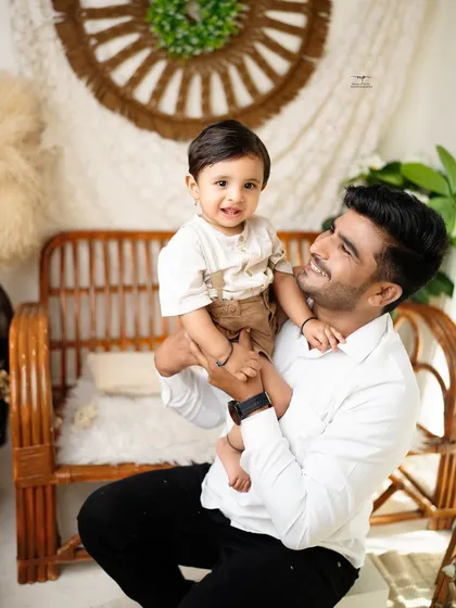 A proud father holds his son, both looking at the camera with bright smiles. This shot highlights the special bond between a dad and his little boy.