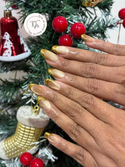 A classic holiday look with a cat-eye base and gold chrome French tips, photographed in front of a Christmas tree to get you in the festive spirit.