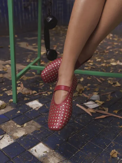 Step into winter with the Red Rivet Ballet Flats. This shot, set against cool blue tiles, makes the warm red leather pop. They are designed to be a bold yet elegant essential for the colder seasons.