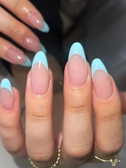 A fresh and fun French manicure with sky blue tips on long, almond-shaped nails. A perfect way to add color to a classic style.