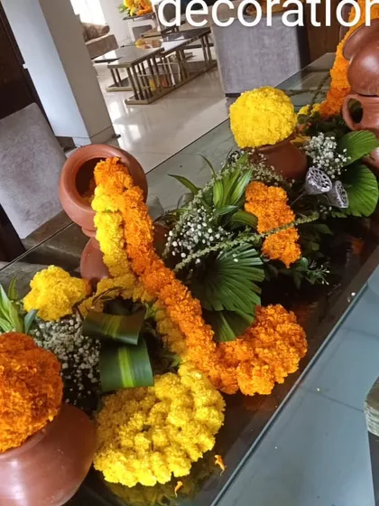 A traditional table runner using marigold balls and garlands, accented with small earthenware pots. This is a perfect setup for a festive meal or puja.