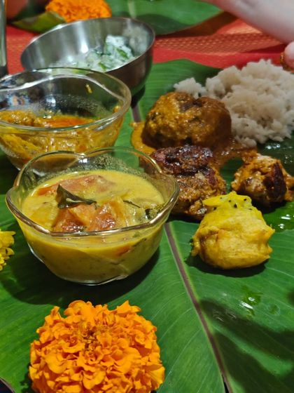 A festive meal served on a banana leaf, decorated with marigold flowers. This thali captures the colours and spirit of celebration, with a variety of curries and snacks that bring warmth and joy to the table.