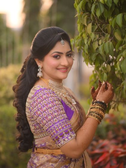 A side profile of the bride, showing her beautiful hairstyle and the detailed embroidery on her purple blouse.