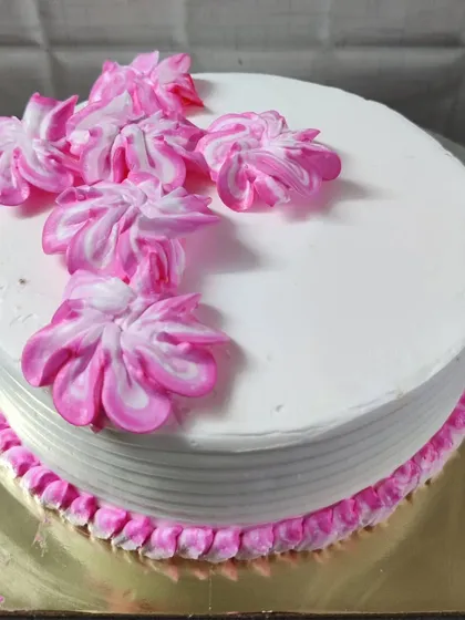 A clean white cake with a simple pink border and beautiful two-tone pink flowers on top.
