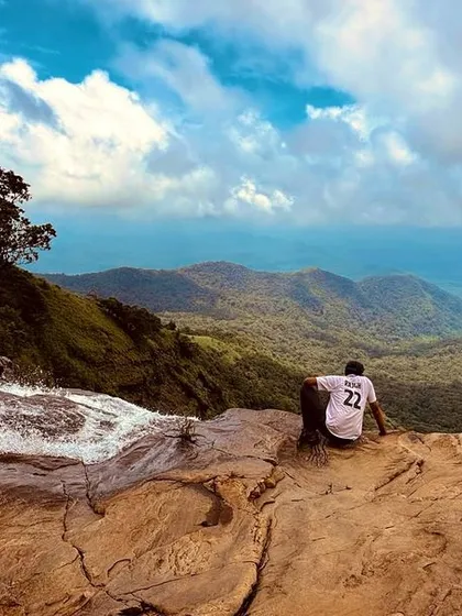 A trekker sitting on the edge of the Bandaje falls viewpoint, looking out at the incredible valley below.
