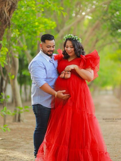 A sweet moment between the couple outdoors. The partner gently places baby shoes on the bump, a lovely gesture of anticipation.