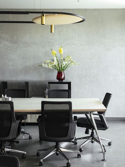 A duplicate image of our conference room, showcasing the minimalist aesthetic and the interplay of textures between the concrete wall, the smooth tabletop, and the soft floral arrangement.