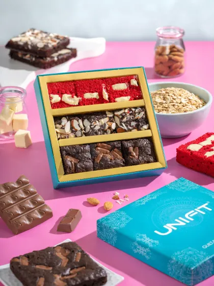 A gift box of assorted brownies, styled with ingredients like chocolate, nuts, and oats to highlight their quality.