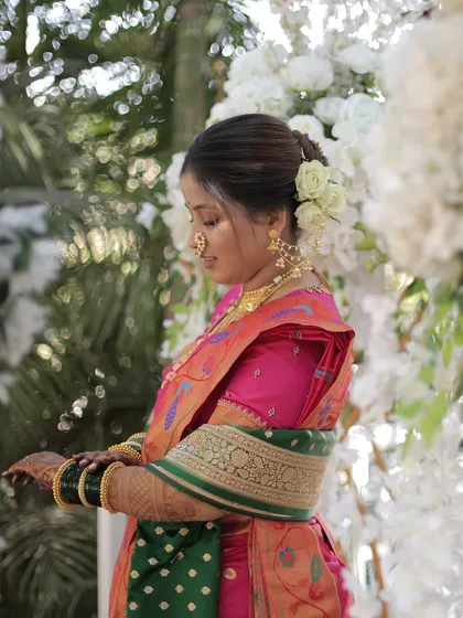 The bride looks down, showcasing her elegant hairstyle adorned with white roses.