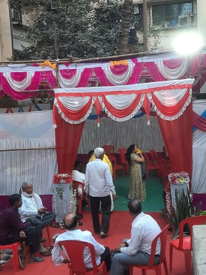 Guests arriving at an outdoor event with a pandal and red carpet entrance.
