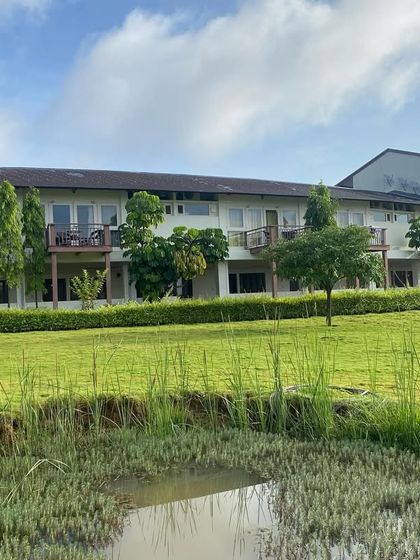 A view of the guest accommodations from across a natural pond. The architecture is designed to blend in, with balconies offering private, uninterrupted views of the serene landscape.