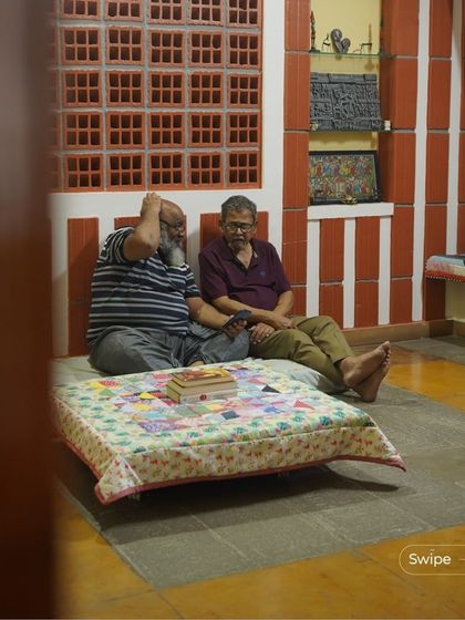 Two residents enjoying a conversation in a space that blends traditional elements like red and white striped walls with comfortable, modern seating. The home is designed for both quiet moments and lively discussions.