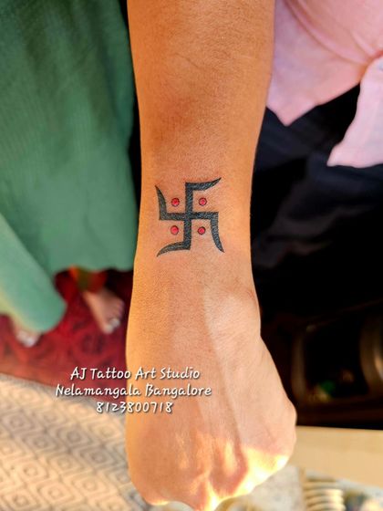 A clean and simple Swastika tattoo on the wrist, a symbol of good fortune and well-being.