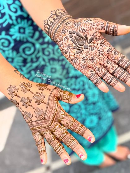 A lovely semi-bridal design with a bold, dark lotus at the center of a dense floral pattern on one hand, and a simpler lotus pattern on the other.