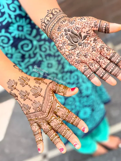 A lovely semi-bridal design with a bold, dark lotus at the center of a dense floral pattern on one hand, and a simpler lotus pattern on the other.
