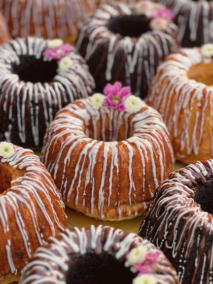 A beautiful array of my mini bundt cakes, drizzled with white chocolate and topped with small flowers. They are perfect as individual desserts or for creating a stunning dessert table.