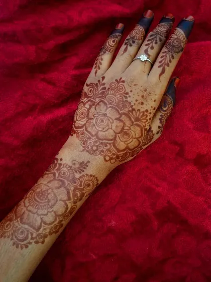 A beautiful rose-themed design on the back of the hand. The shading on the roses gives them depth, and the pattern extends from the wrist to the fingers.