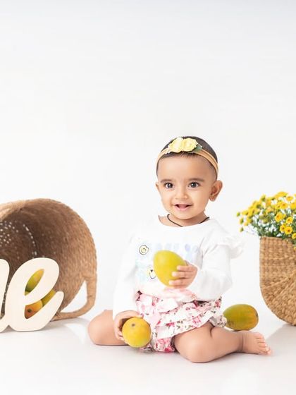 The full setup for the mango themed shoot, with baskets of fruit and a "one" sign. This is a great example of a creative, non cake smash first birthday session.