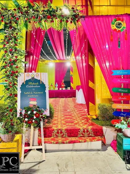 A grand entrance for a colorful Mehndi night. I used bright pink and yellow drapes, a floral arch, and a personalized welcome sign to greet the guests.