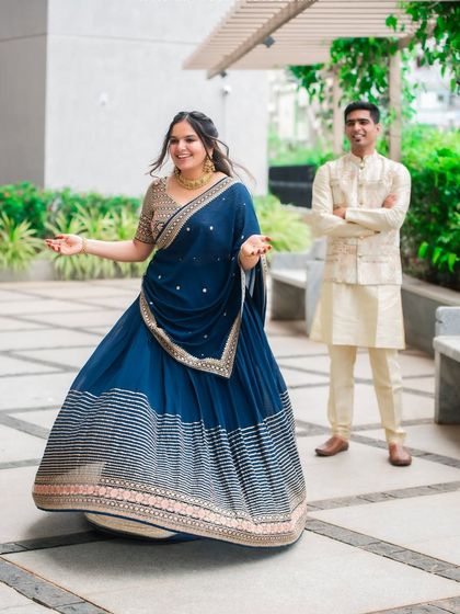 This couple's radiant smiles are the highlight of their ethnic wear photoshoot. The rich blue of the lehenga and the classic cream kurta create a picture of pure elegance.