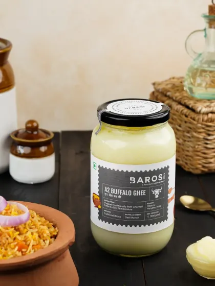 A lifestyle shot of A2 Buffalo Ghee next to a bowl of flavorful biryani, suggesting a perfect pairing for rich, traditional dishes.