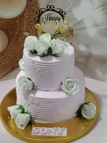 A classic two-tiered cake with a textured buttercream finish and white sugar roses. A simple, elegant design that's perfect for any celebration.