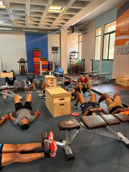 A wider view of the team's recovery session. Utilizing various equipment like benches and boxes, the athletes are guided through breathwork to calm the system after intense training.