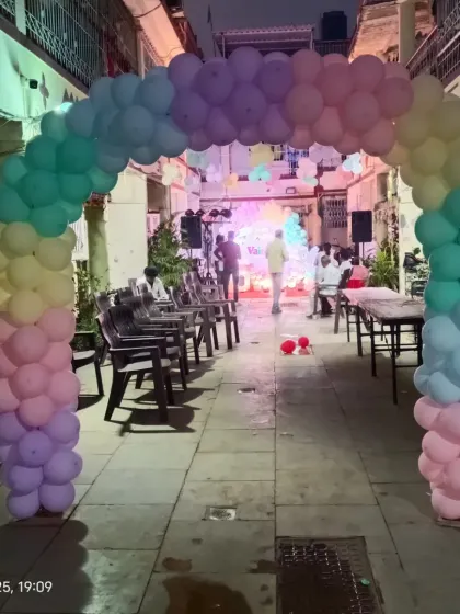 The entrance to the unicorn-themed party, held in an outdoor space, with a pastel rainbow balloon arch leading to the main event area.